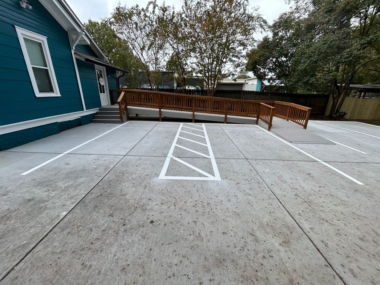Freshly painted ADA access aisle with white diagonal hatching beside an accessible parking space