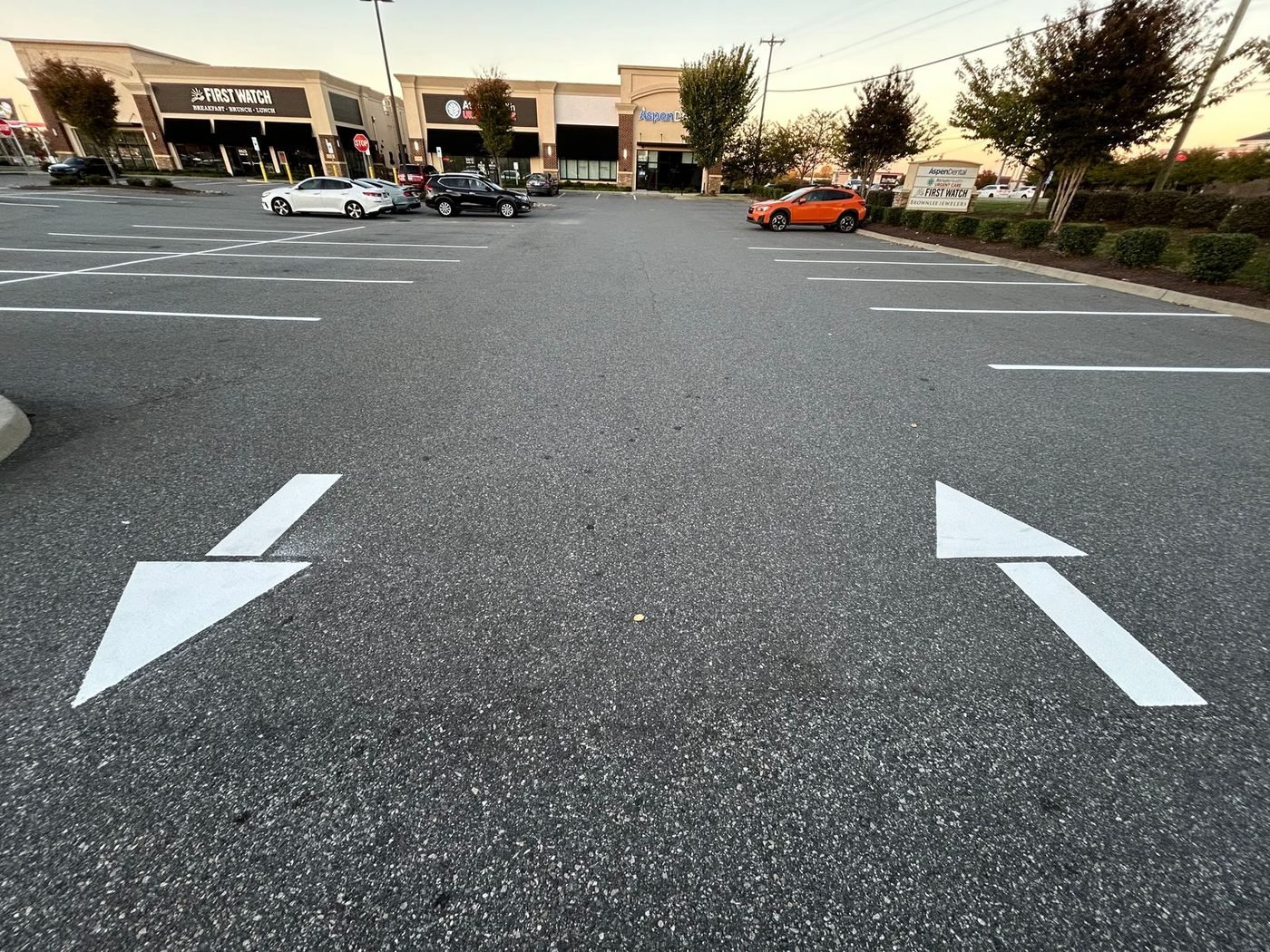 Newly painted directional traffic arrows guiding vehicles through a retail parking lot