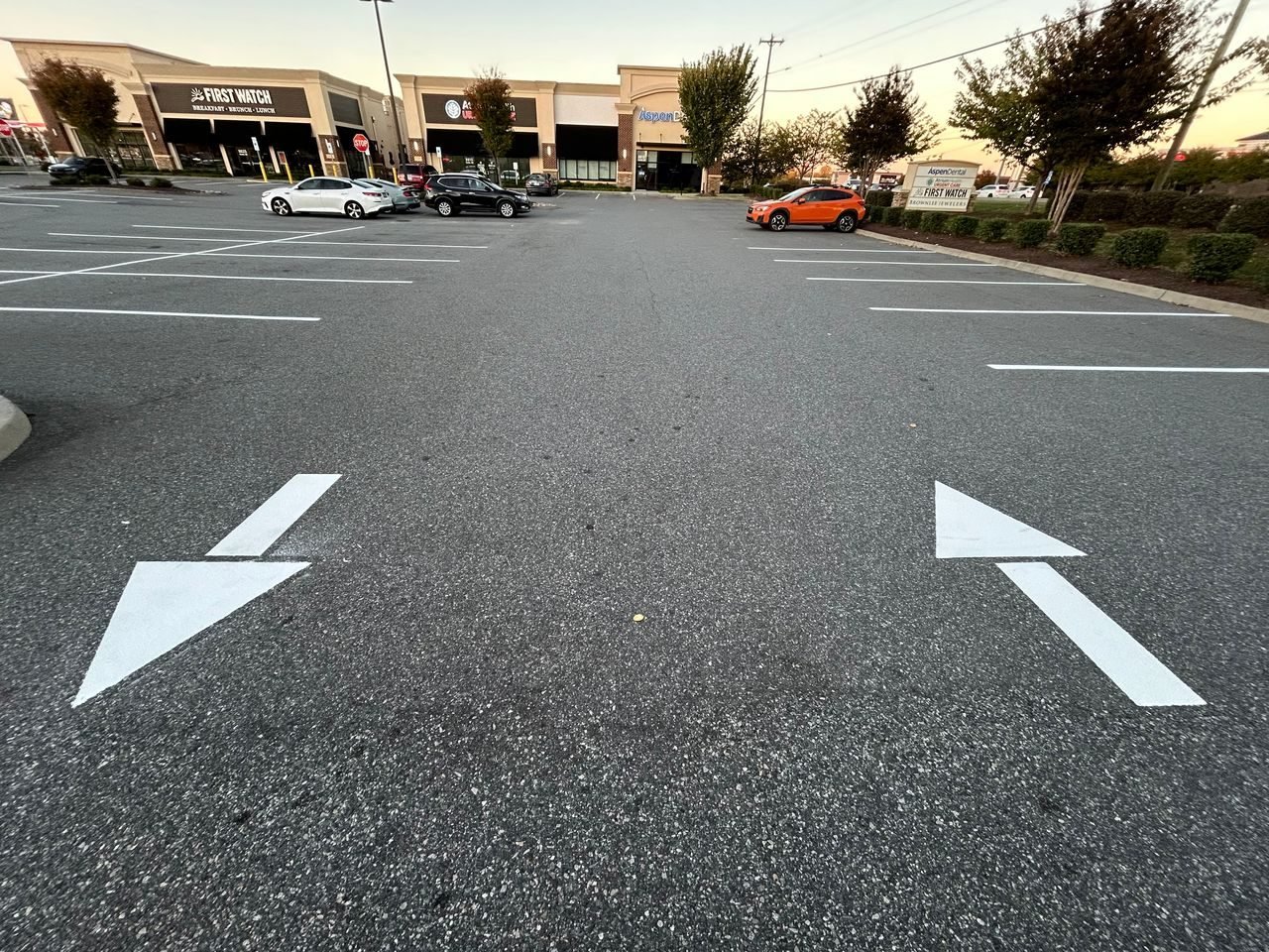 Bright white directional arrows painted on fresh asphalt at a retail shopping center
