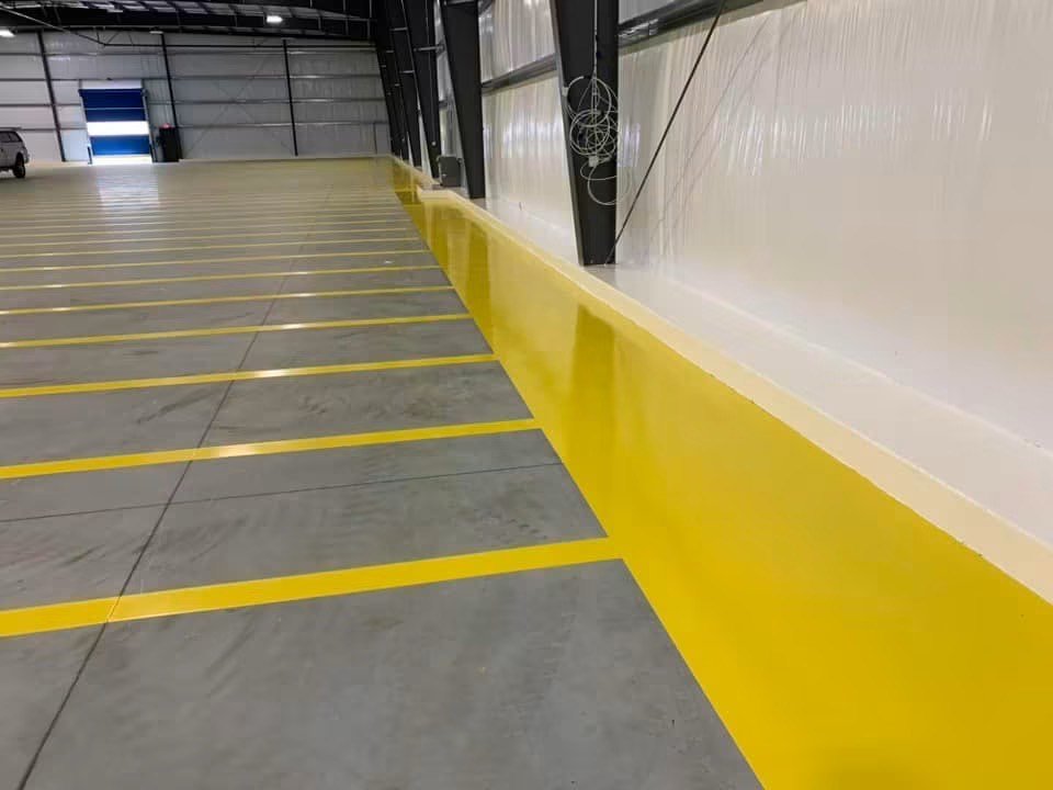 Yellow floor lines and a painted yellow safety kerb running along a warehouse wall